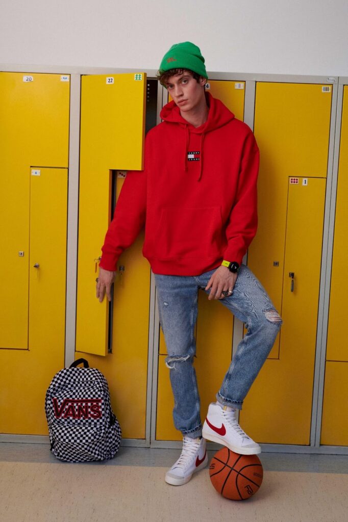 chlapec v džínách, červené mikině, beanie čepici a sneakers Nike