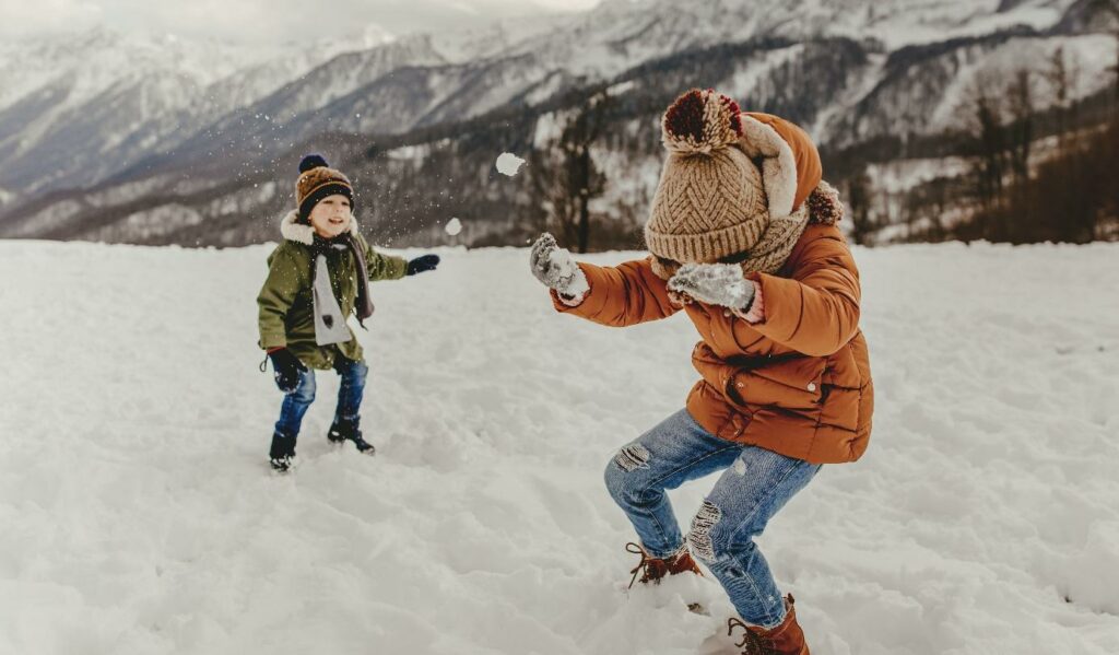 Chlapci si hrají ve sněhu v dětských zimních bundách.