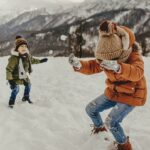 Chlapci si hrají ve sněhu v dětských zimních bundách.