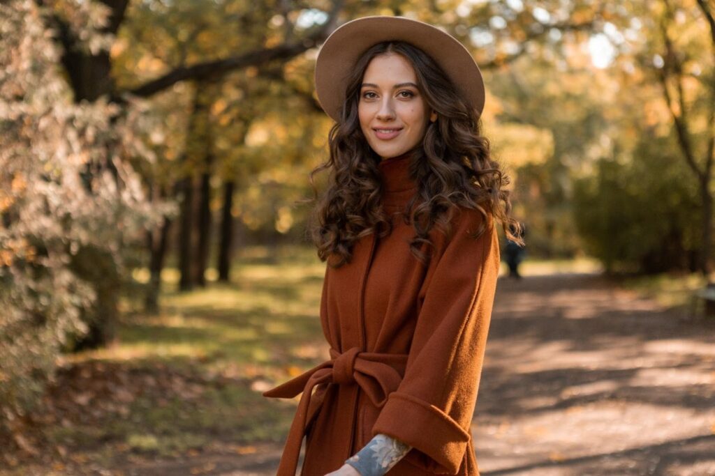 Dívka v parku v hnědém kabátě a světle hnědém klobouku