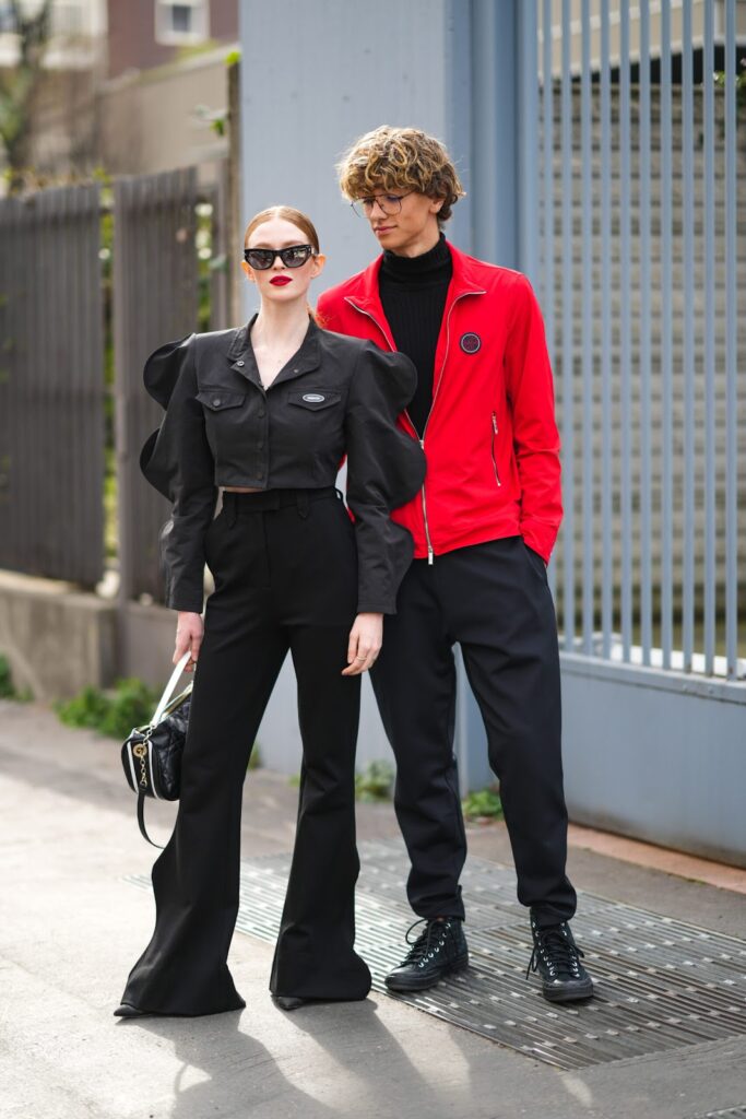 žena v černém total look a muž v černém roláku, černých kalhotách a červené bundě