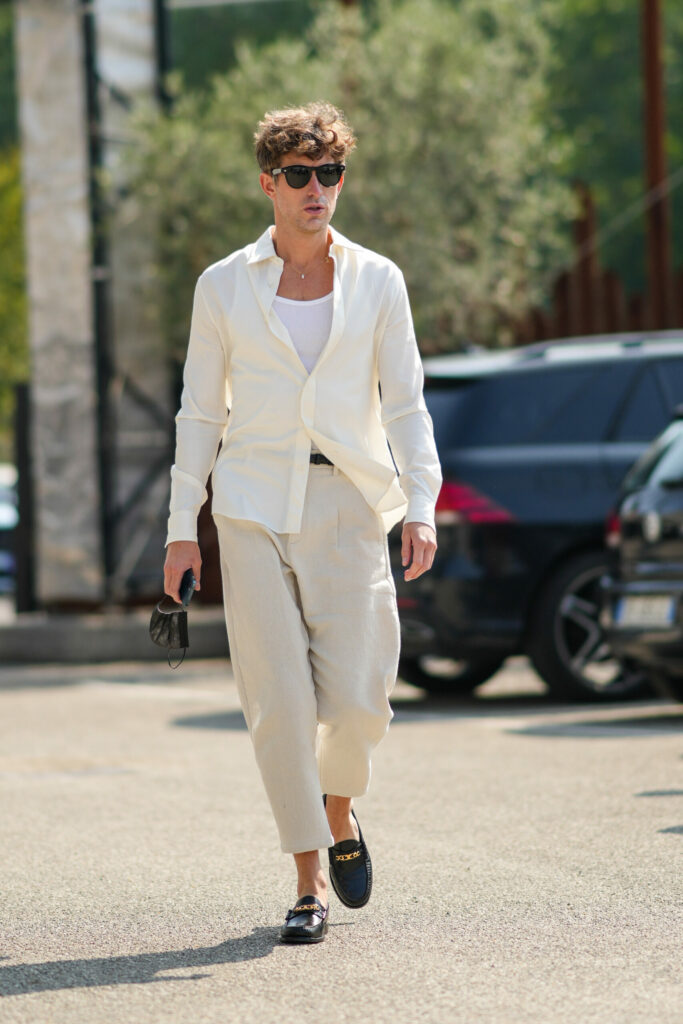 Muž, který jde po ulici. Má na sobě lněné kalhoty a bílou košili.