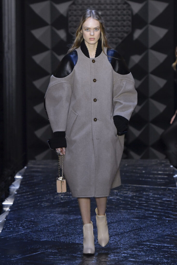 modelka v šedém oversize kabátu s koženými vsadkami
