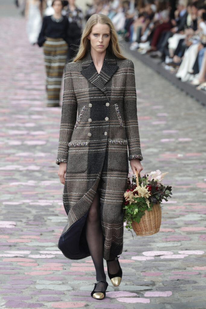modelka na přehlídkovém mole Chanel v kostkovaném kabátě

