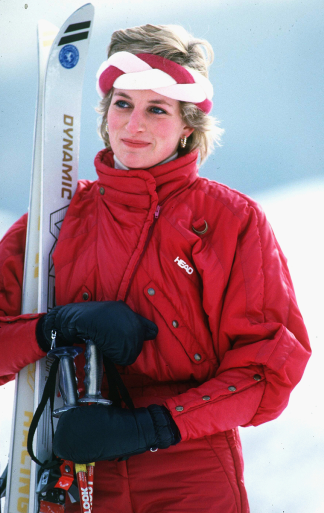 Princezna Diana v předlyžařském outfitu s červenou lyžařskou bundou HEAD, pletenou čelenkou a lyžemi DYNAMIC