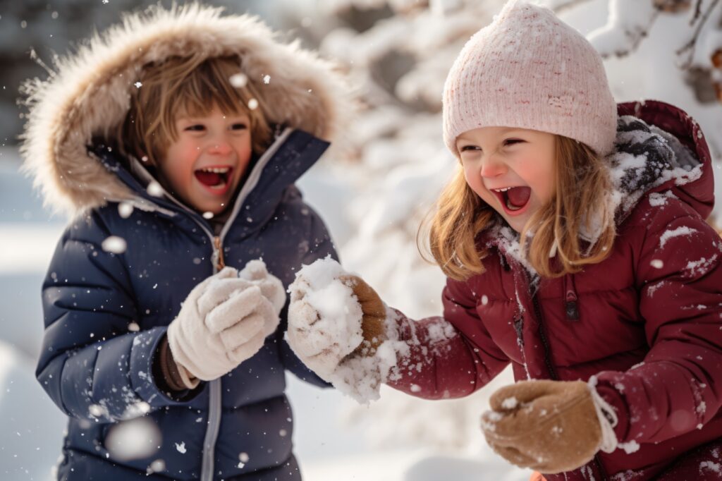Chlapec a dívka si hrají ve sněhu v dětských péřových bundách