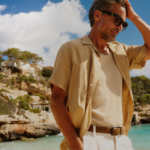 muž na pláži ve světlých kalhotách a lněné košili s krátkým rukávem