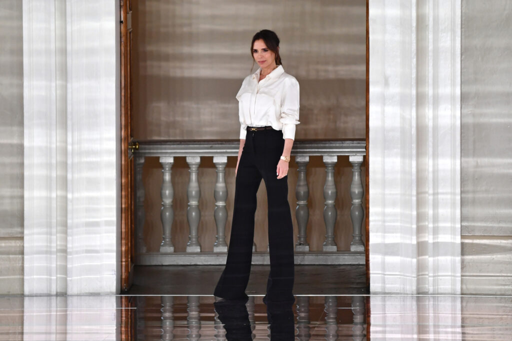 Victoria Beckham v bílé košili a černých kalhotách s vysokým pasem